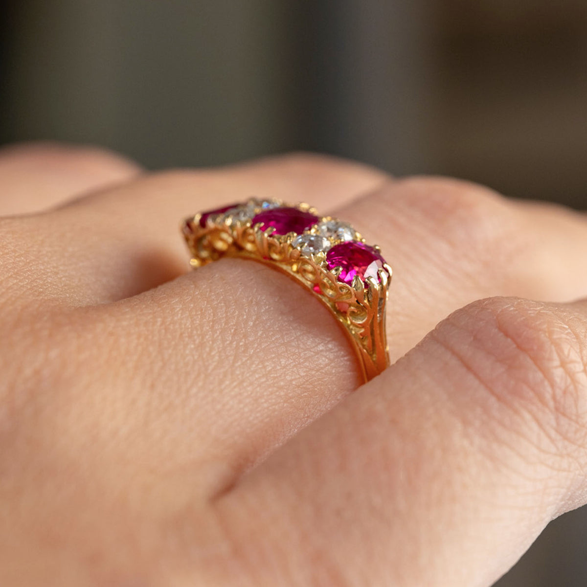 Low side angle of the Edwardian engagement ring, revealing its raised stones and intricate openwork yellow gold gallery.