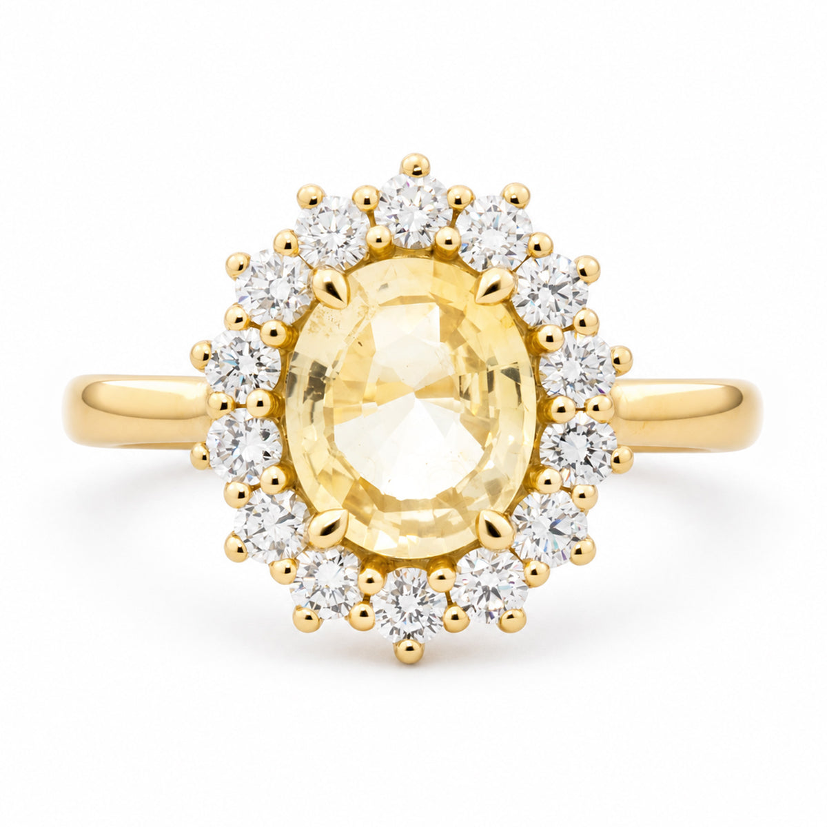 An antique-inspired, pale yellow sapphire and diamond cluster engagement ring set in 14ct yellow gold.