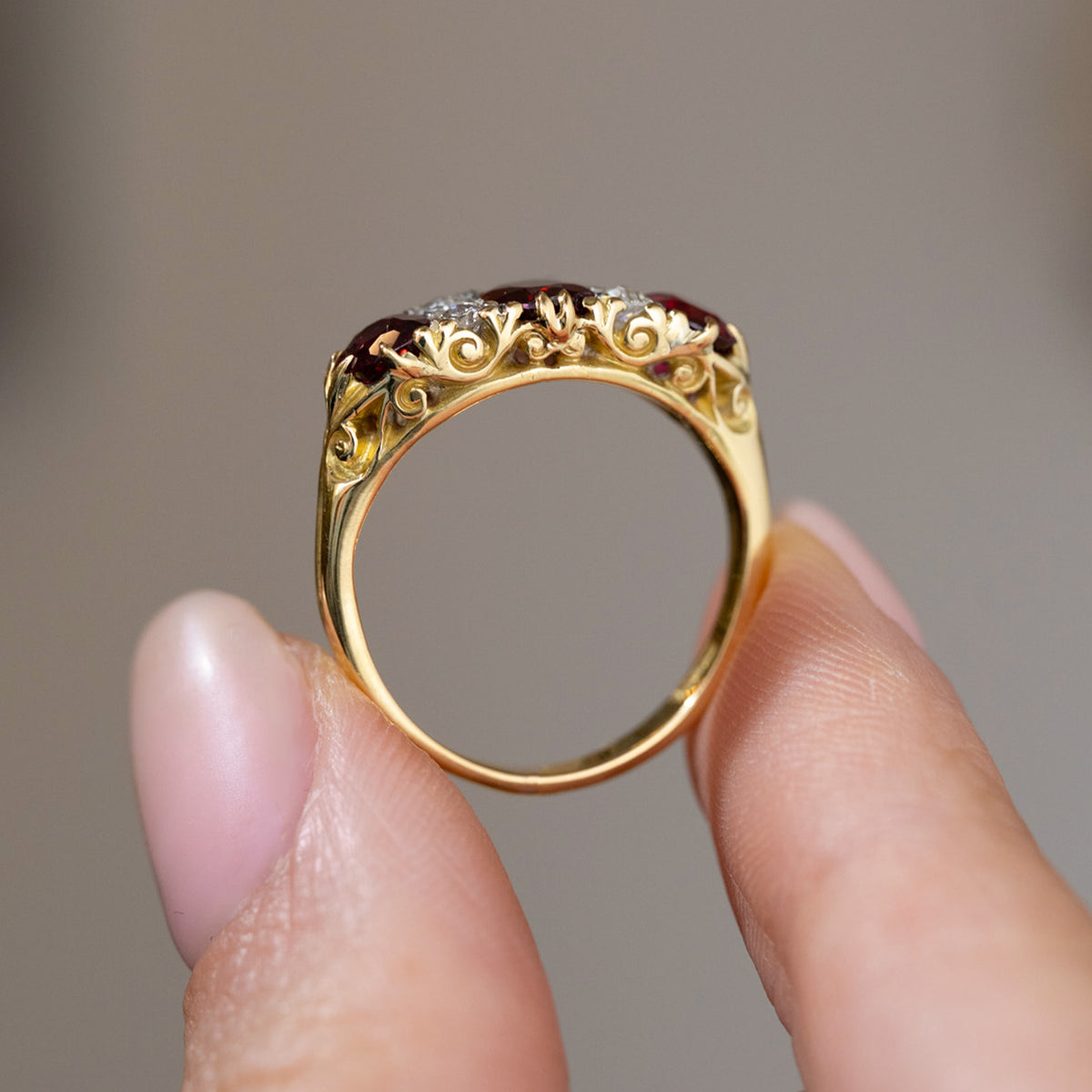 Profile view of the Victorian three-stone ring, showing the intricate scrolling gallery and polished yellow gold shank.