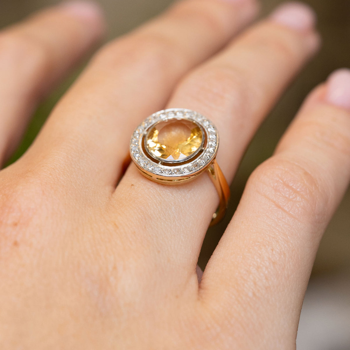 Antique French citrine cluster engagement ring worn at an angle, showing the warm yellow stone and delicate rose-cut diamond border.