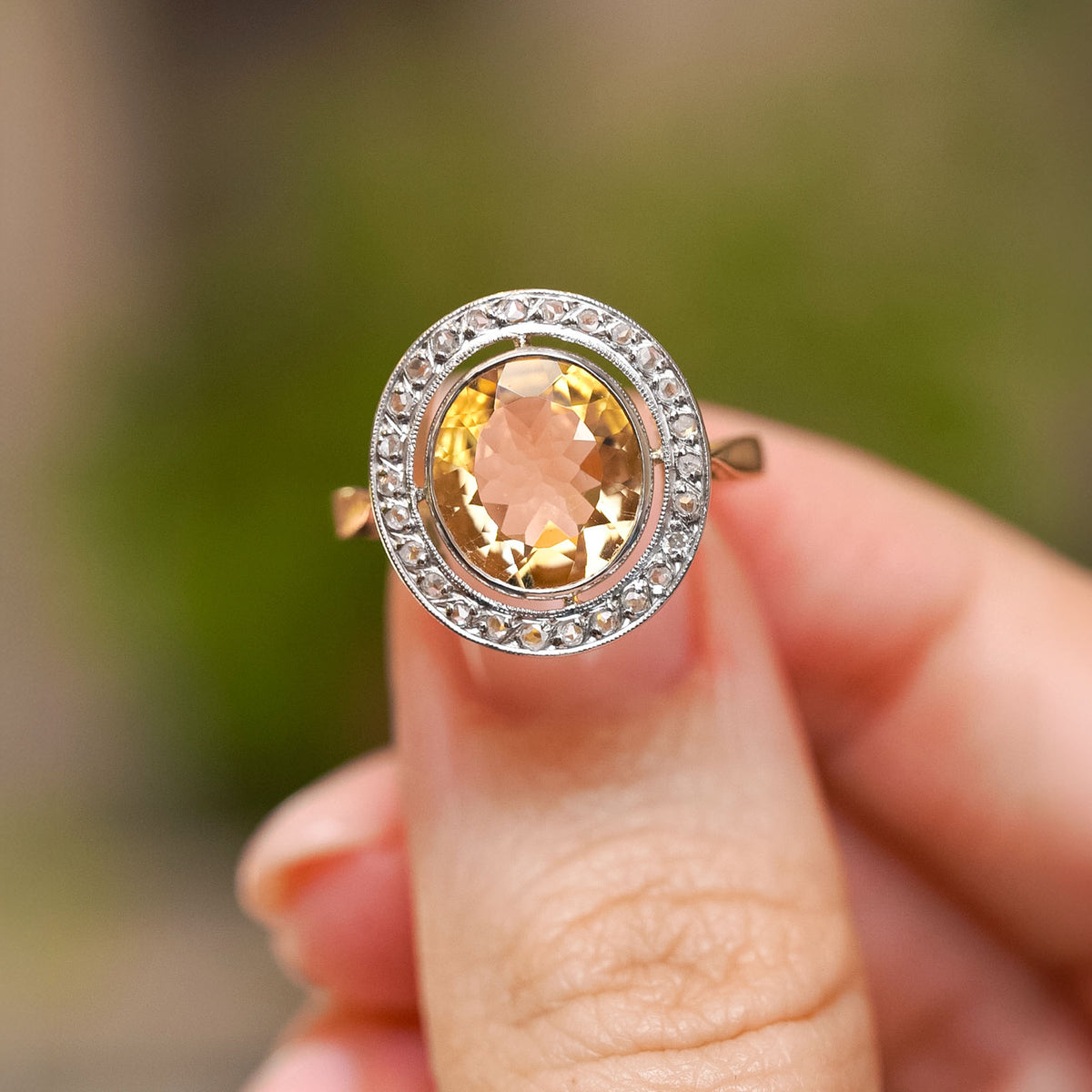 Close-up of a French Belle Époque citrine cluster ring, with a golden yellow gemstone encircled by antique rose-cut diamonds.