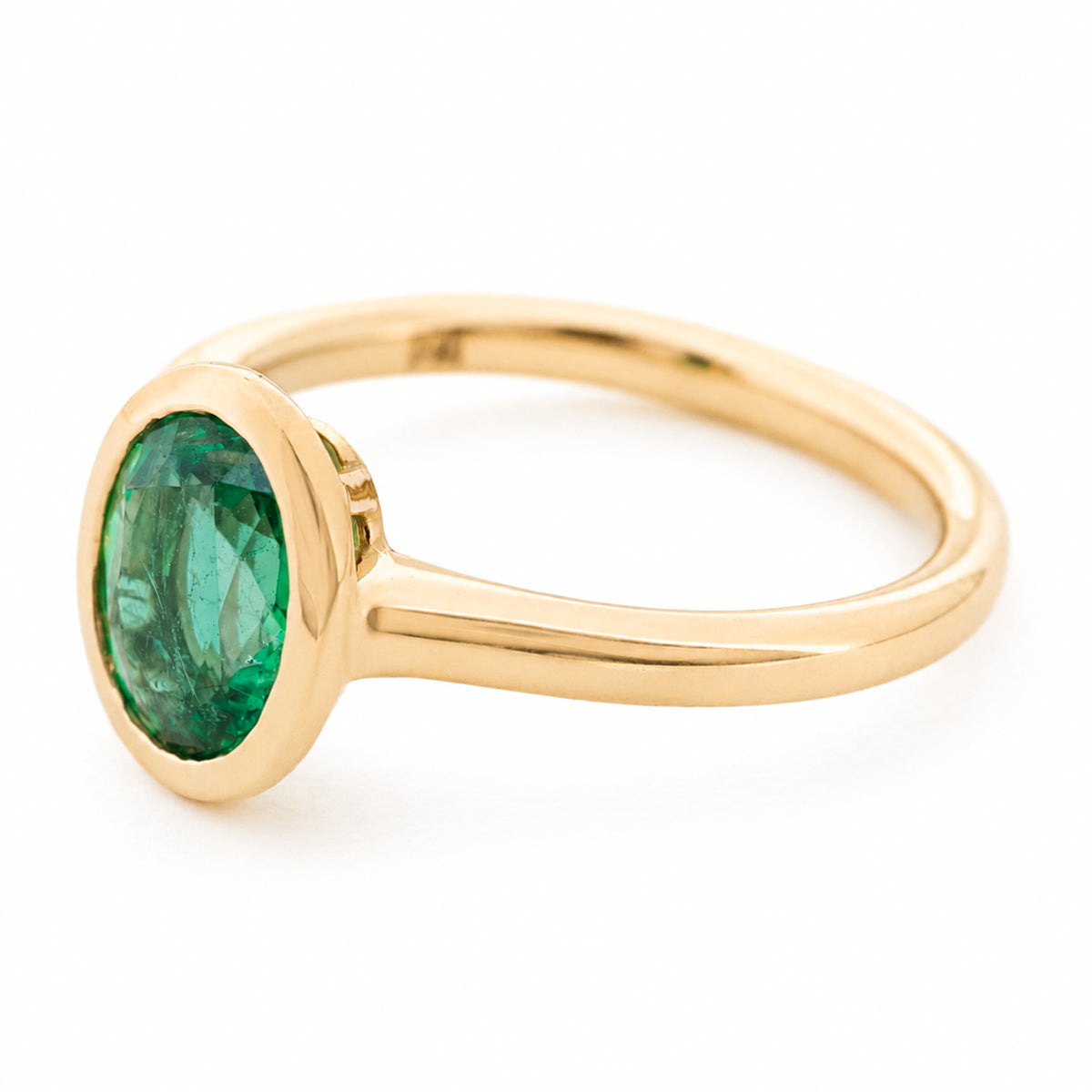 A side profile of a vintage-inspired yellow gold engagement ring featuring an oval emerald.