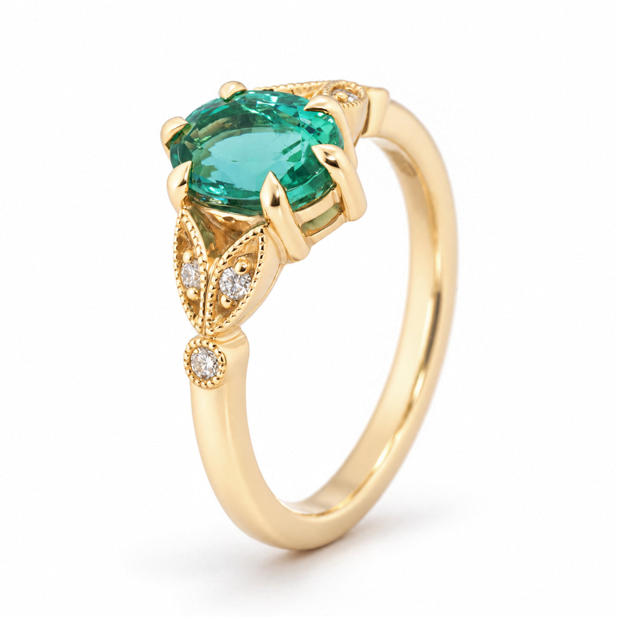 Angled view of a vintage-inspired emerald engagement ring in yellow gold, showcasing its oval green emerald, decorative diamond-set trefoil shoulders and delicate detailing.