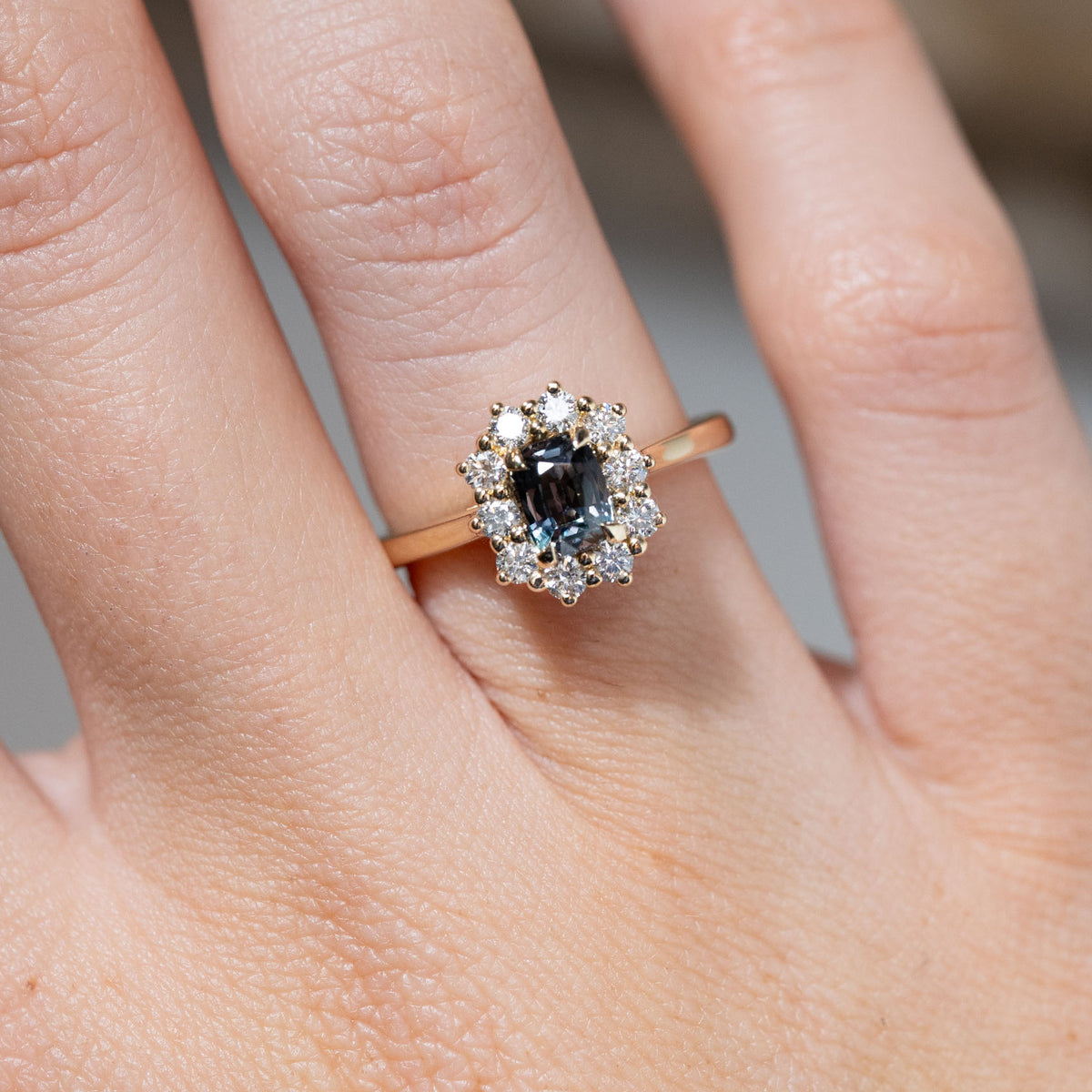 Close-up of the rectangular blue sapphire framed by brilliant-cut white diamonds, worn on a finger.