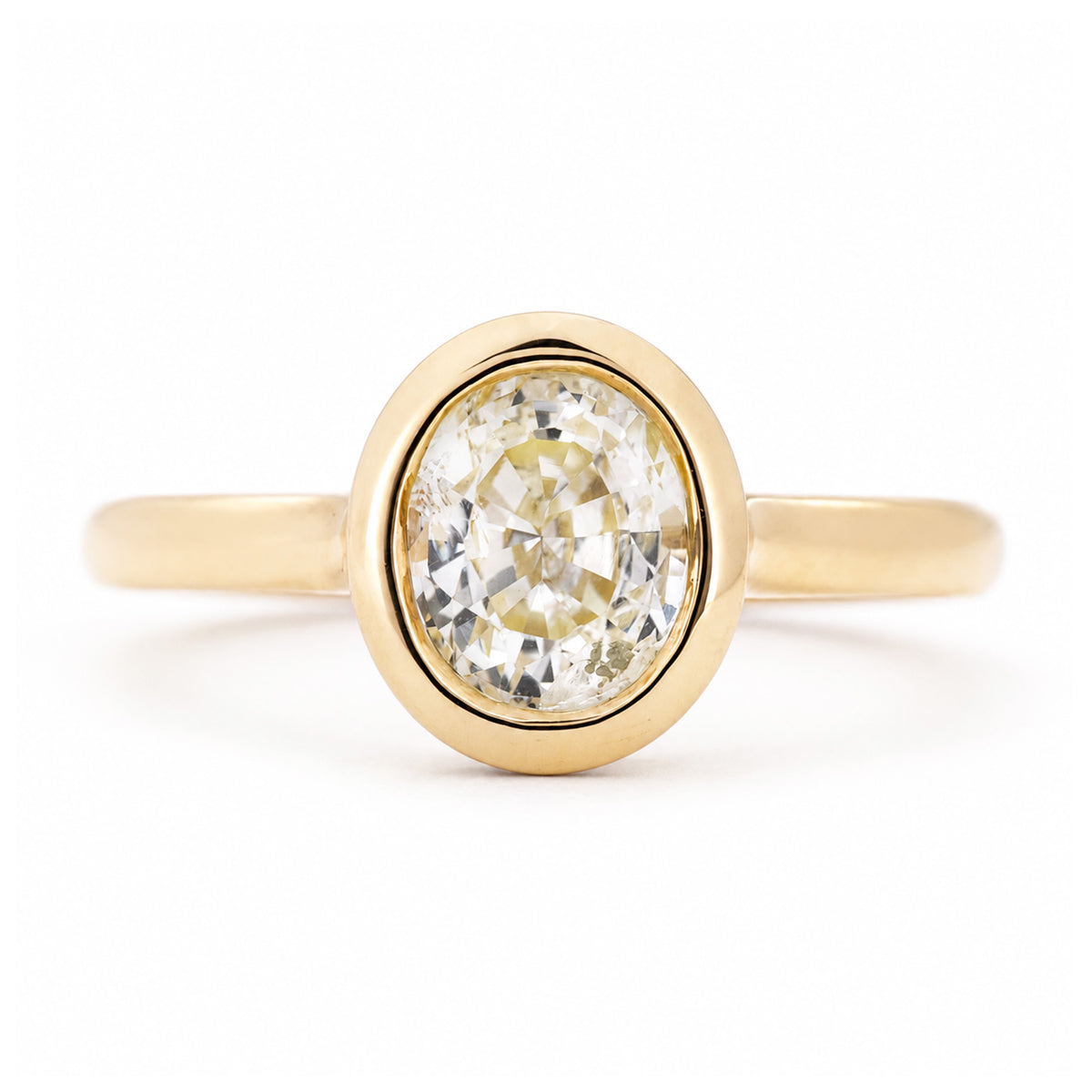 An antique-inspired, pale yellow sapphire solitaire engagement ring set in yellow gold.