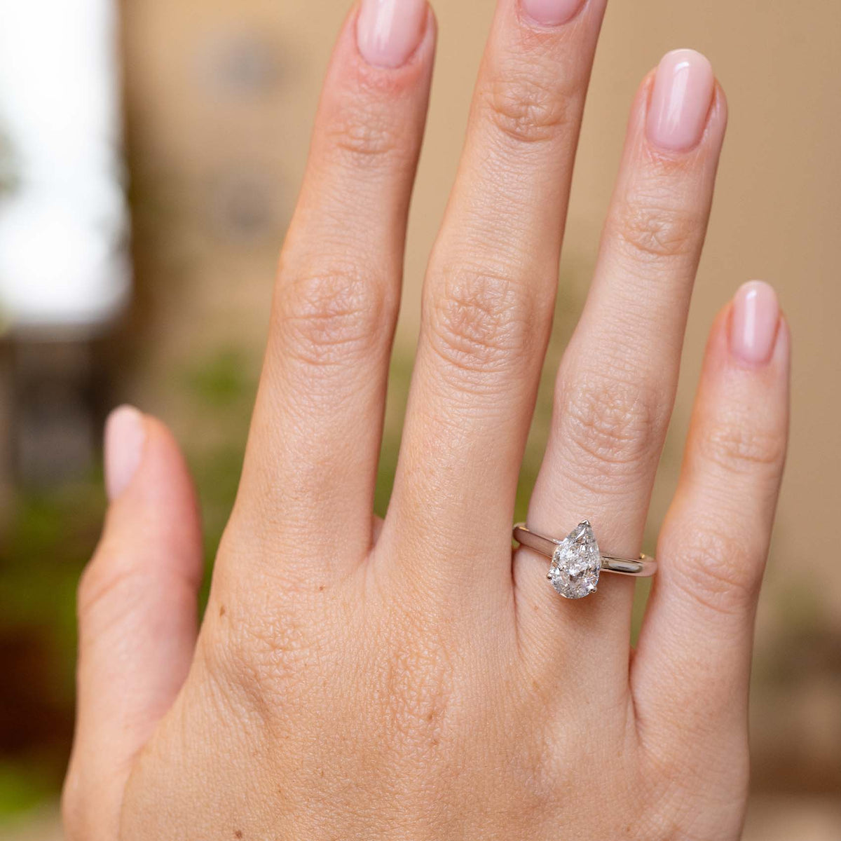 Vintage 1990s salt and pepper diamond solitaire worn on the hand, showcasing its elegant pear cut and slim white gold band.
