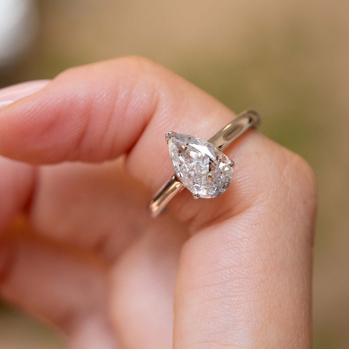 Vintage salt and pepper diamond engagement ring worn on a finger, showcasing the stone’s unique natural inclusions and pear shape.
