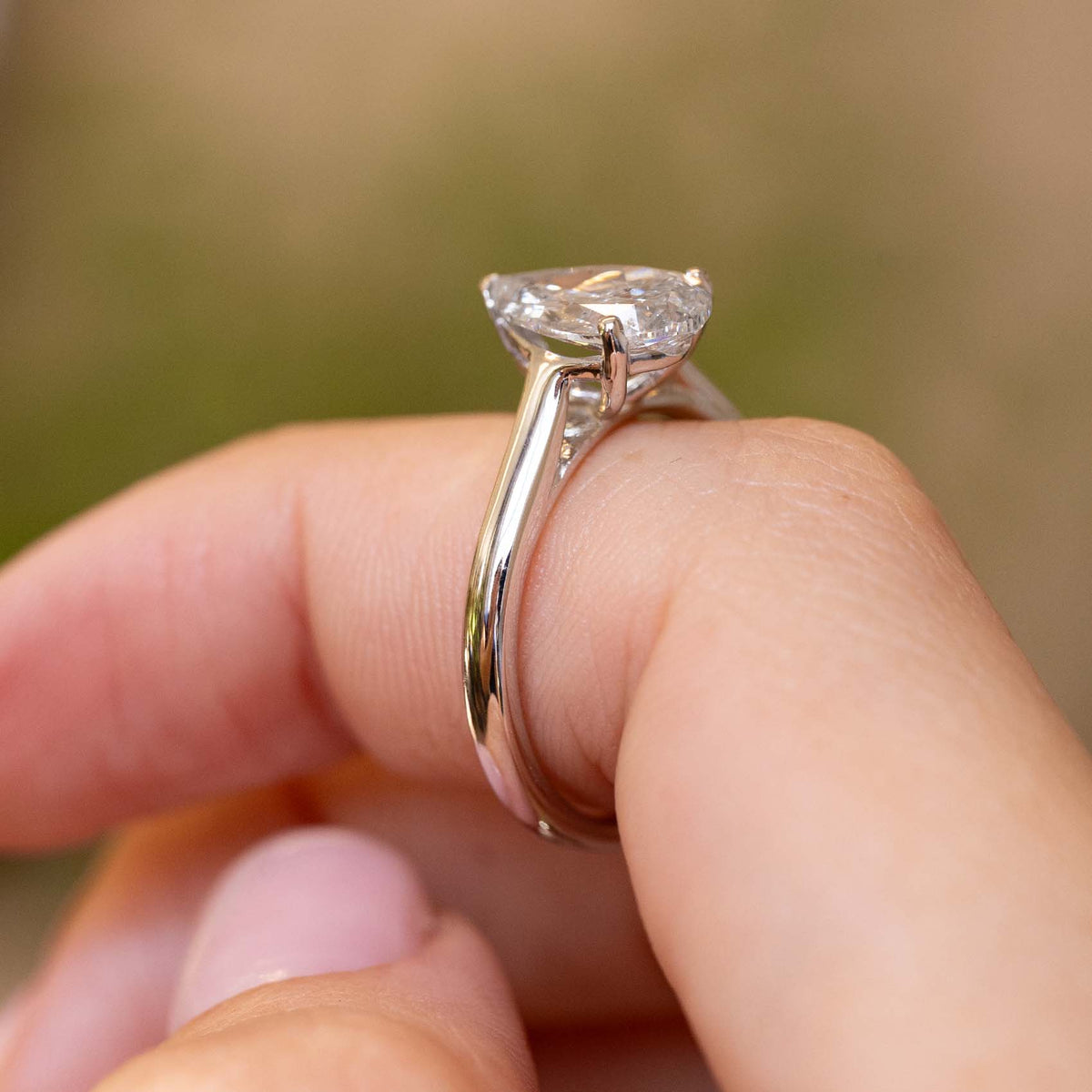 Profile view of a vintage 1990s diamond solitaire ring, highlighting the elevated pear-cut setting and polished white gold band.