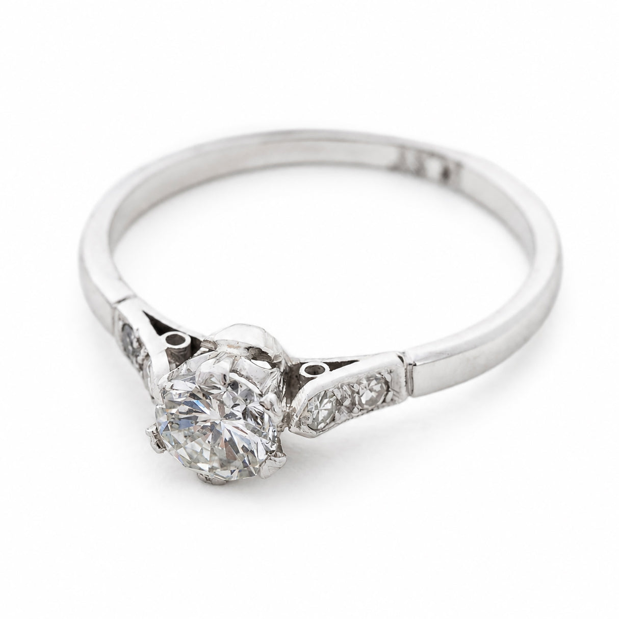 A three-quarter view of an Art-Deco platinum ring set with a natural round diamond at the centre.