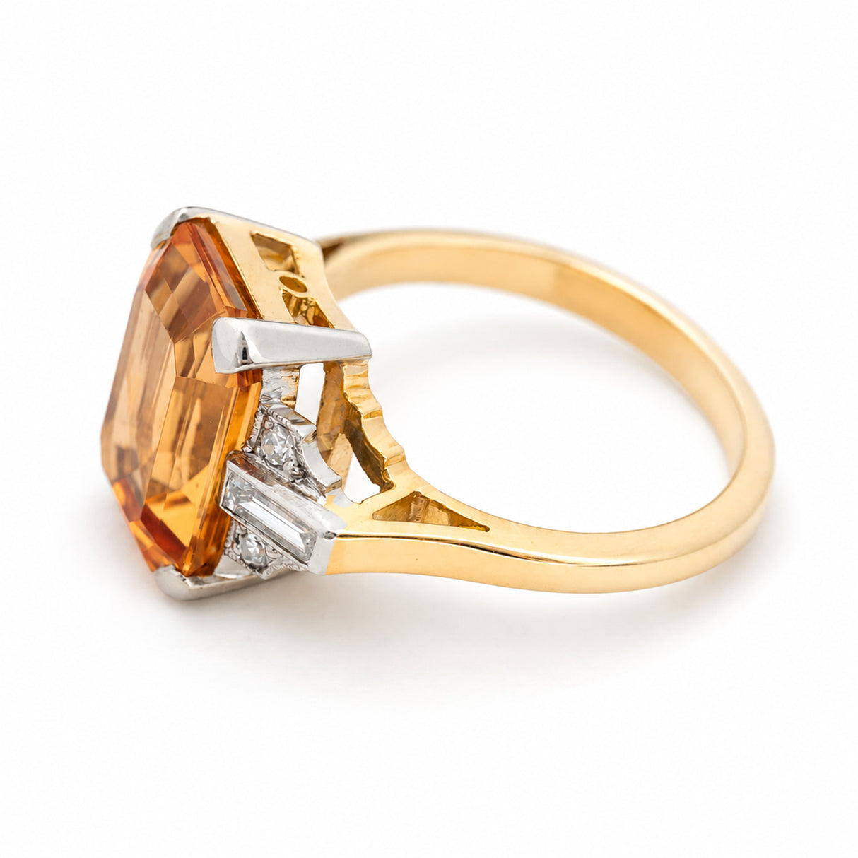 A yellow gold vintage engagement ring with orange topaz and diamonds shown from an elevated angle against a white background.