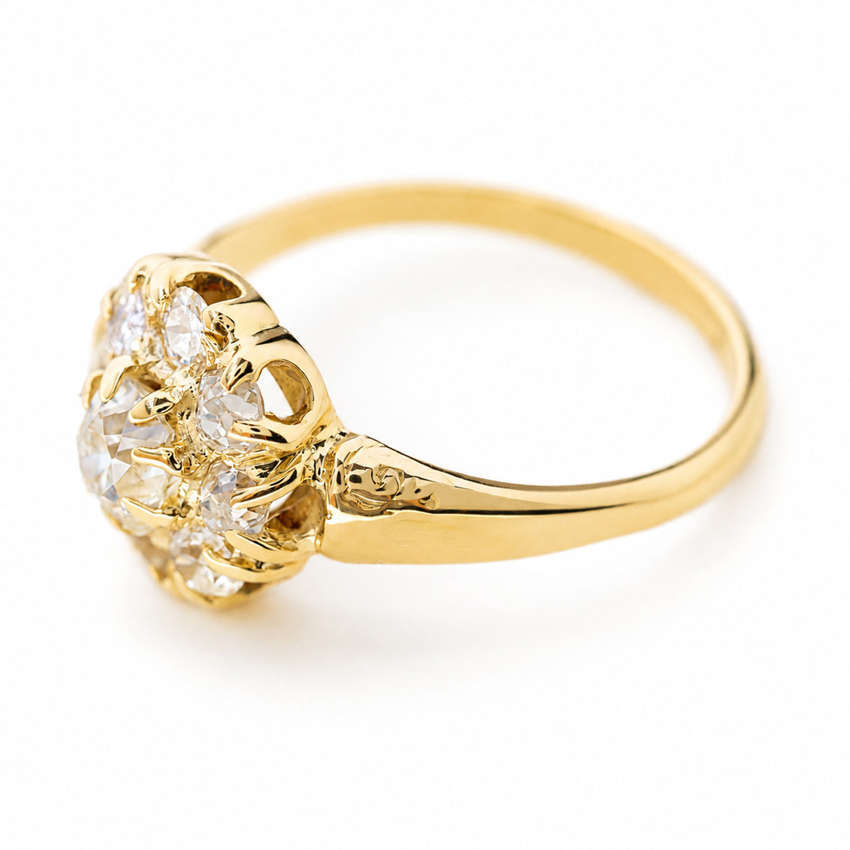 A Victorian old cut diamond cluster engagement ring in yellow gold shown at an angle against a plain white background to showcase the claw setting style and gallery.