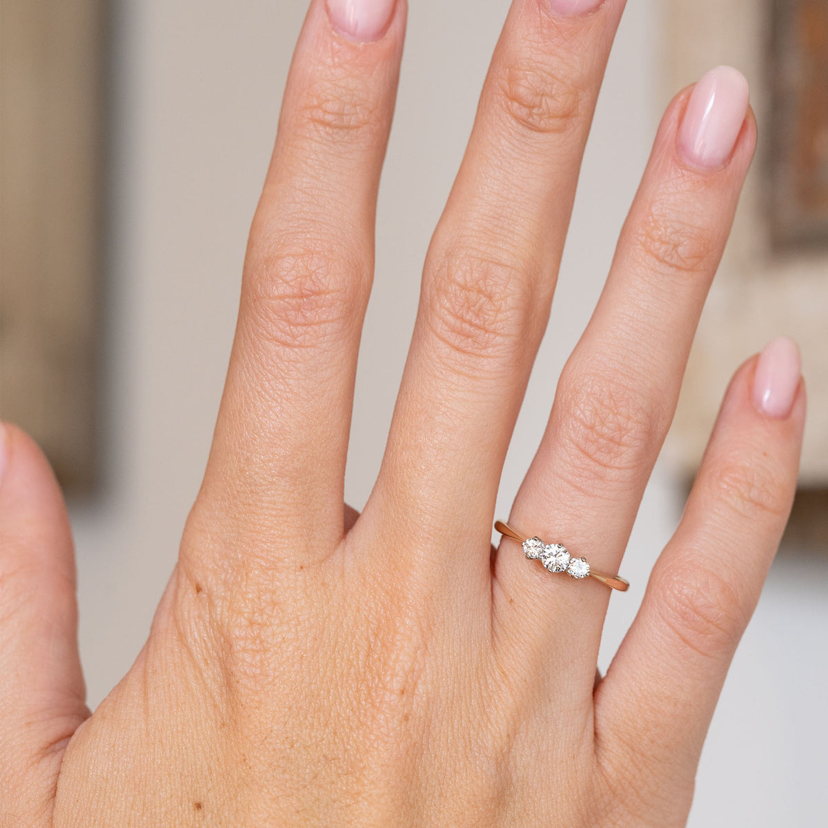 Antique three-stone diamond engagement ring worn on the hand, showing its elegant scale and two-tone design.