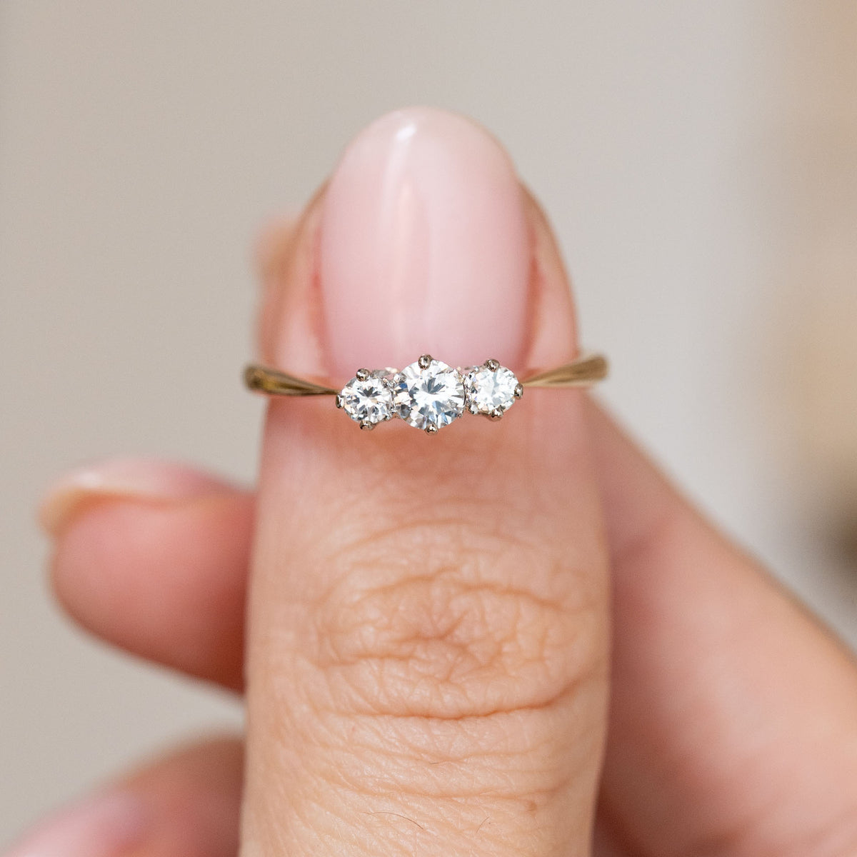 Antique diamond trilogy ring displayed across the fingertip, offering a clear look at the graduated three-stone arrangement.
