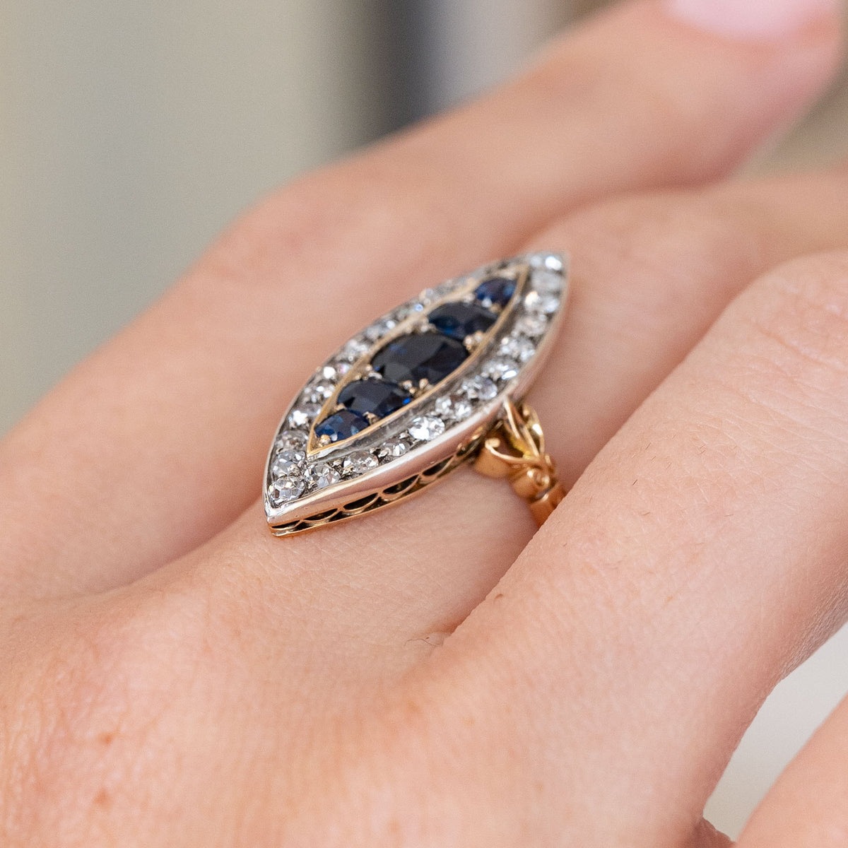 Viewed from the side on the finger, the ring displays its elevated silver setting and ornate yellow gold under-gallery.