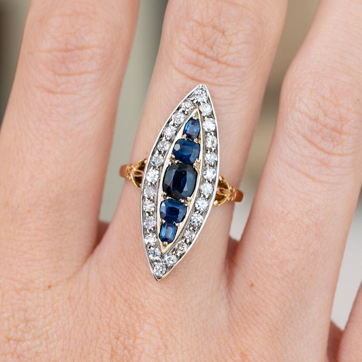 An intimate worn detail highlights the varied sapphire cuts arranged along the centre of the elongated diamond cluster.
