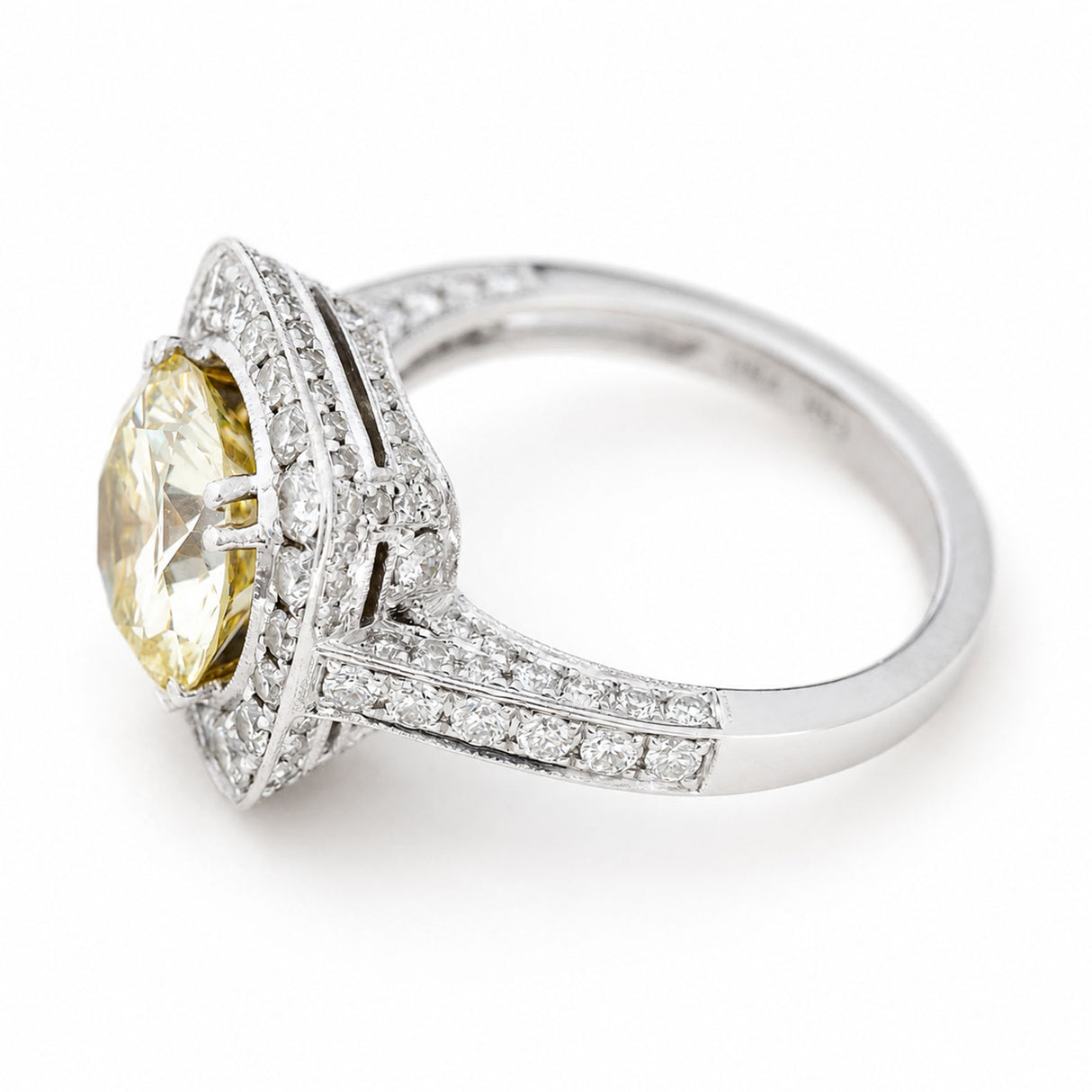 A white goldVintage, 1990s yellow tinted diamond cluster engagement ring against a white background at an angle to show off its diamond-set bezel