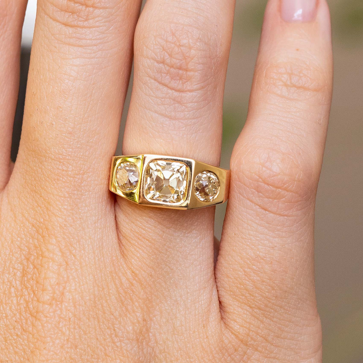 A Vintage, 1970s Peruzzi cut diamond three-stone gypsy ring shown worn on a person's finger.