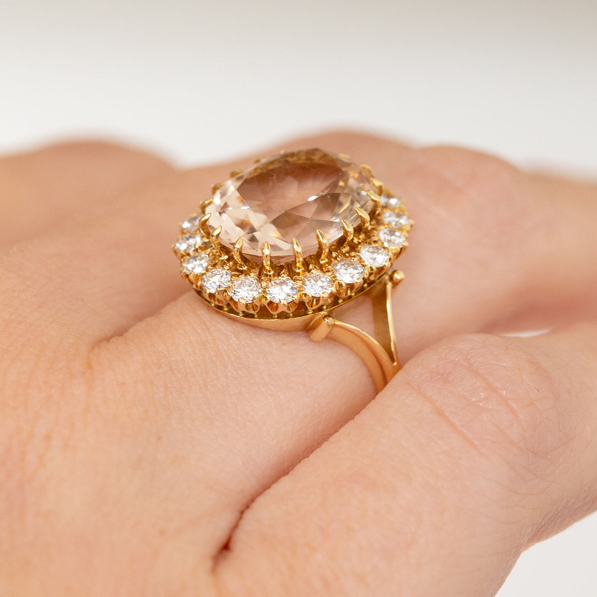 Side-angled hand view of the vintage engagement ring, displaying the elevated topaz and diamond setting above the yellow gold shank.