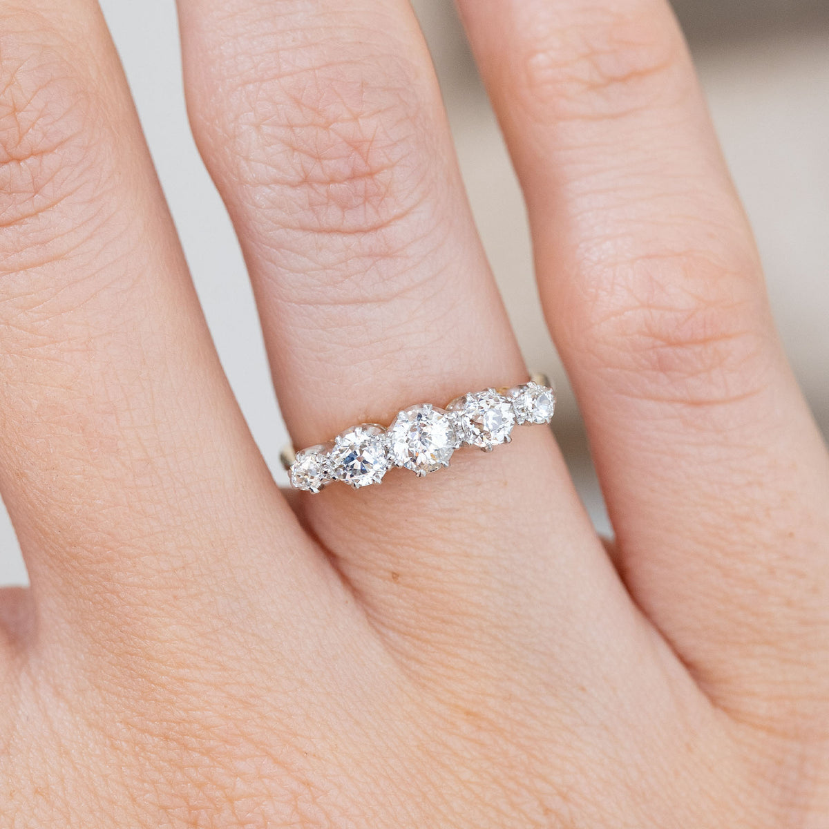 Detailed hand close-up showing the larger central diamond tapering into smaller old-cut stones on either side.