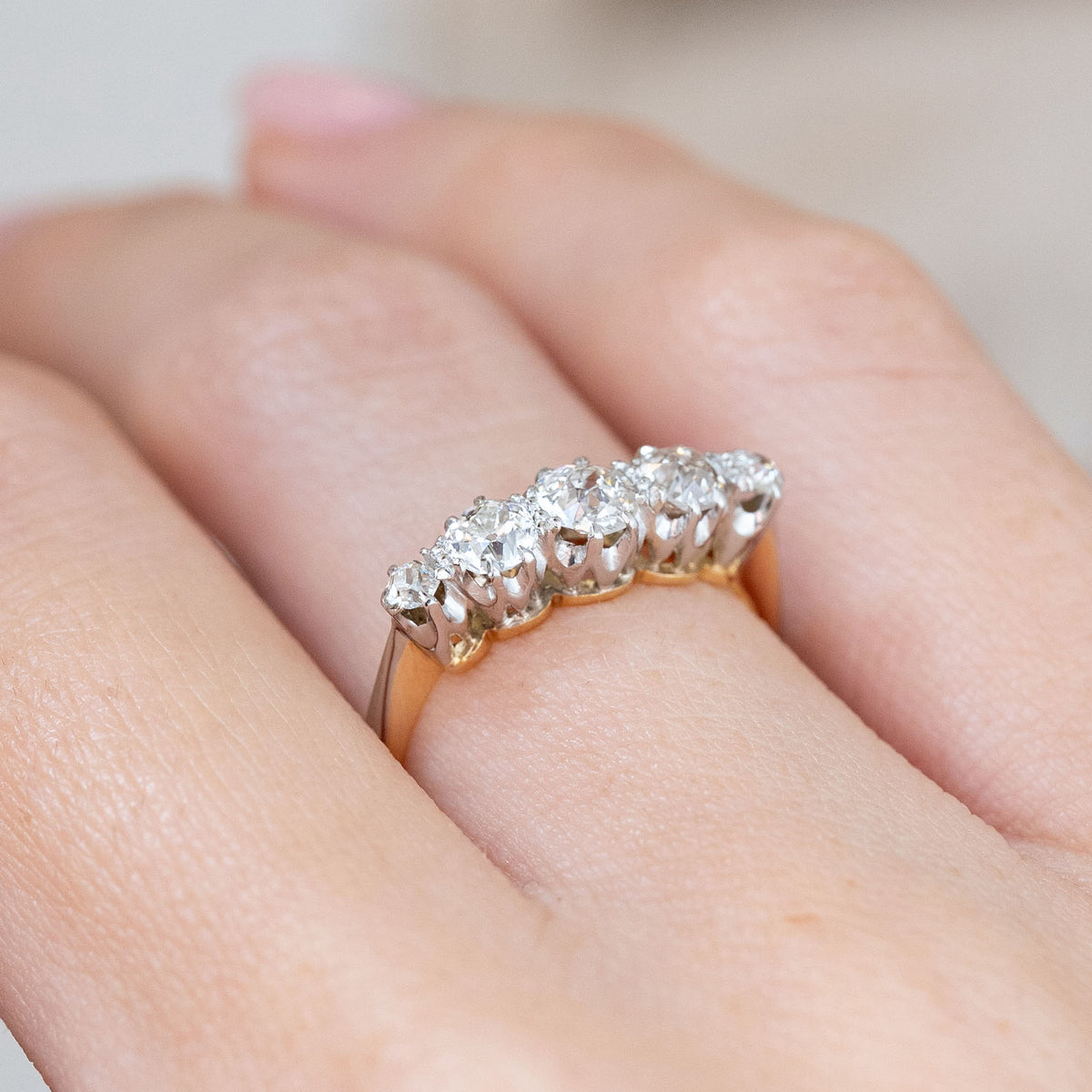 An oblique worn perspective reveals the elevated row of five diamonds and the contrasting yellow gold under-gallery.