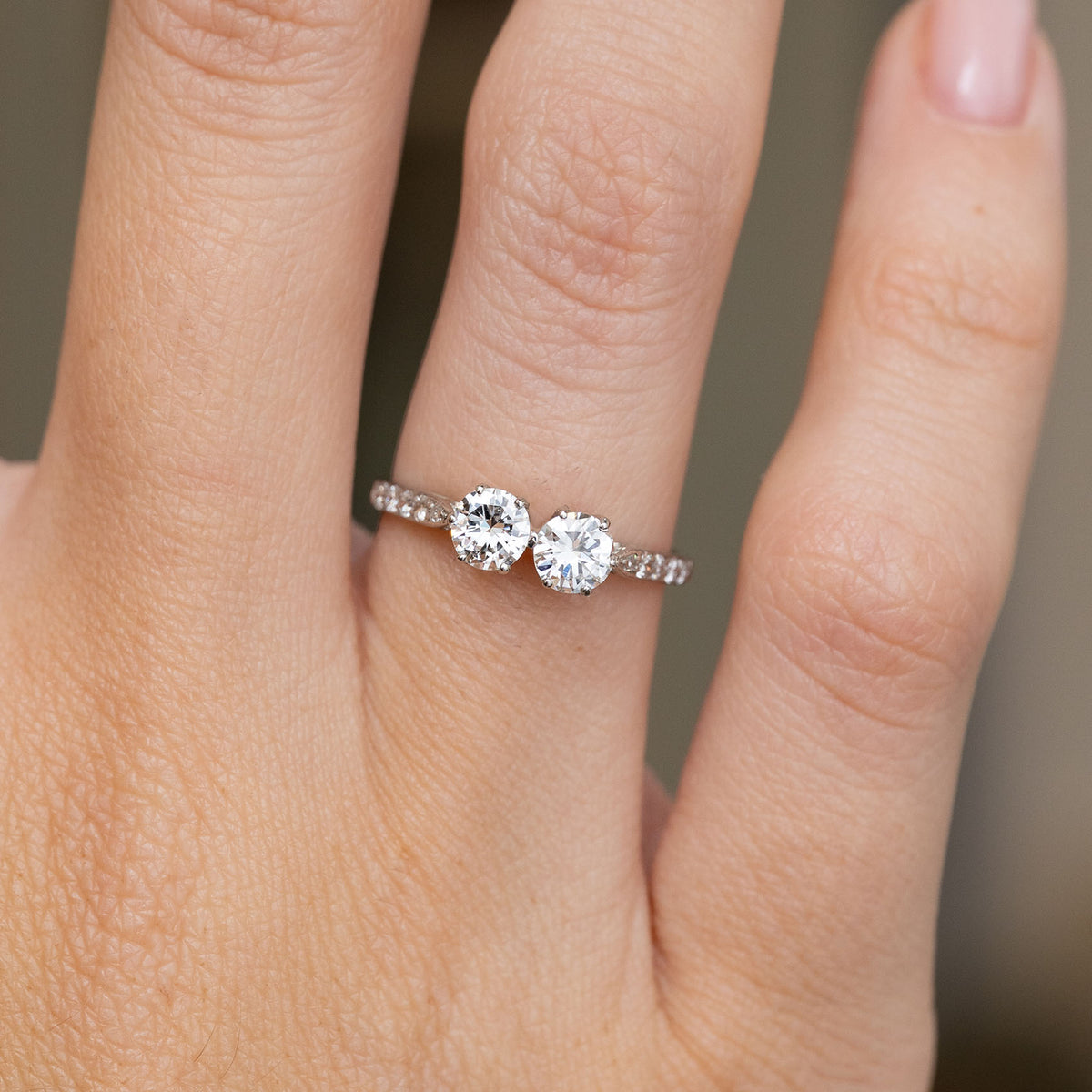 Close hand detail of two round transition-cut diamonds set side by side on a diamond-accented platinum band.