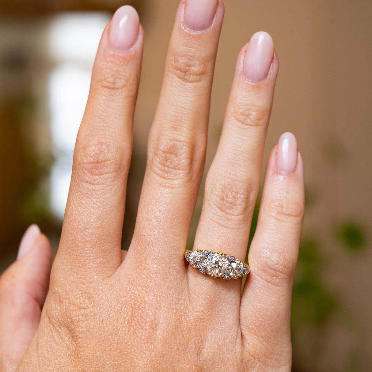 Full-hand view of the antique three-stone engagement ring, with its diamond-set face spanning gracefully across the finger.