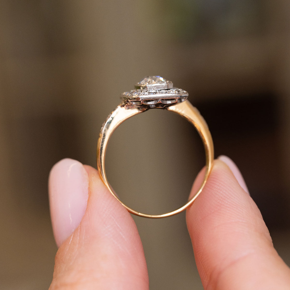 Profile view of an Edwardian diamond engagement ring, revealing the raised platinum cluster and polished yellow gold band.