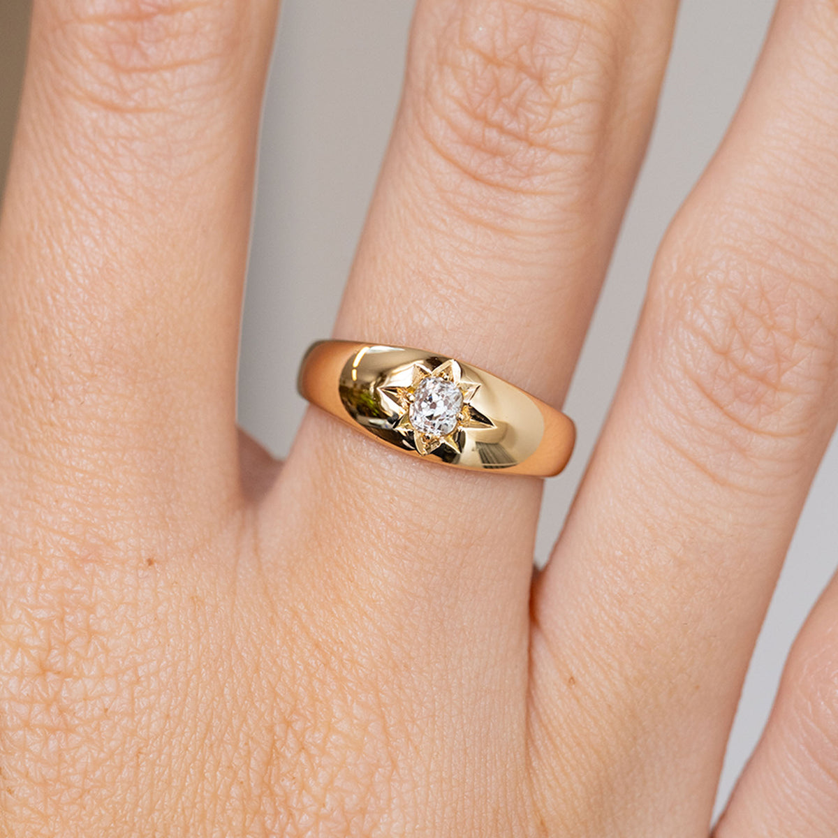 Detailed view of the antique diamond solitaire worn on the finger, with its distinctive starburst engraving.