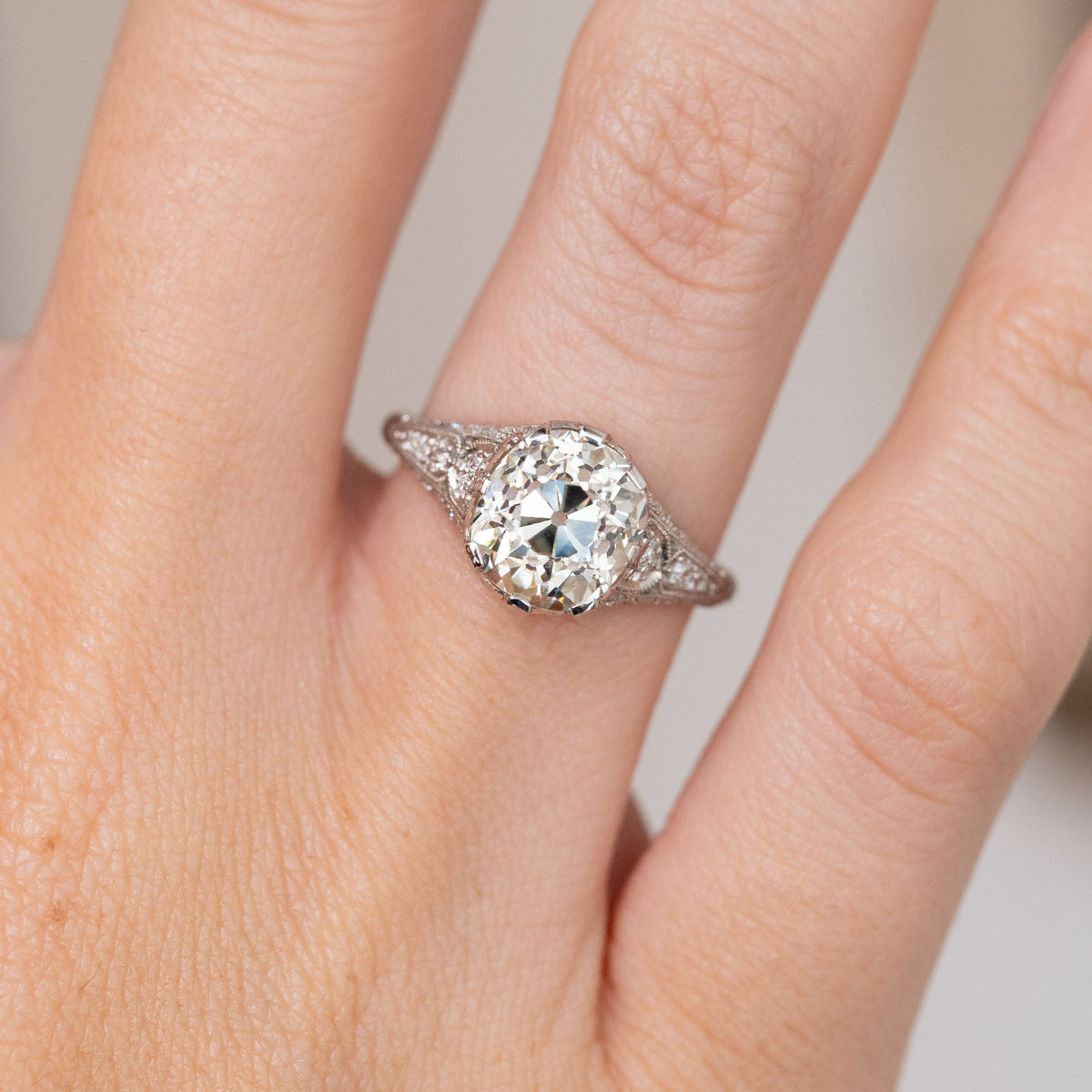 Close-up on-hand view highlighting the large antique diamond, triangular shoulders and fine milgrain borders.