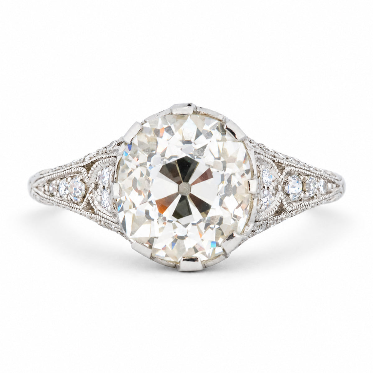 Antique Edwardian old-mine cut diamond solitaire engagement ring with diamond-set shoulders and delicate milgrain detailing.