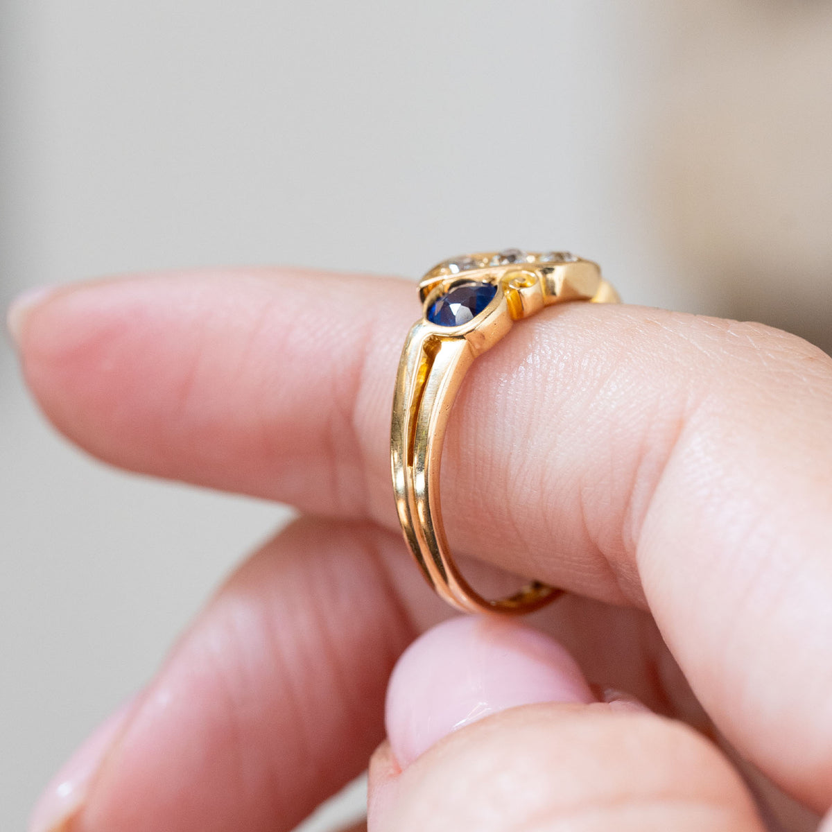 Side profile displaying the low sculptural mount, polished yellow gold shank and dimensional arrangement of the five gemstones.
