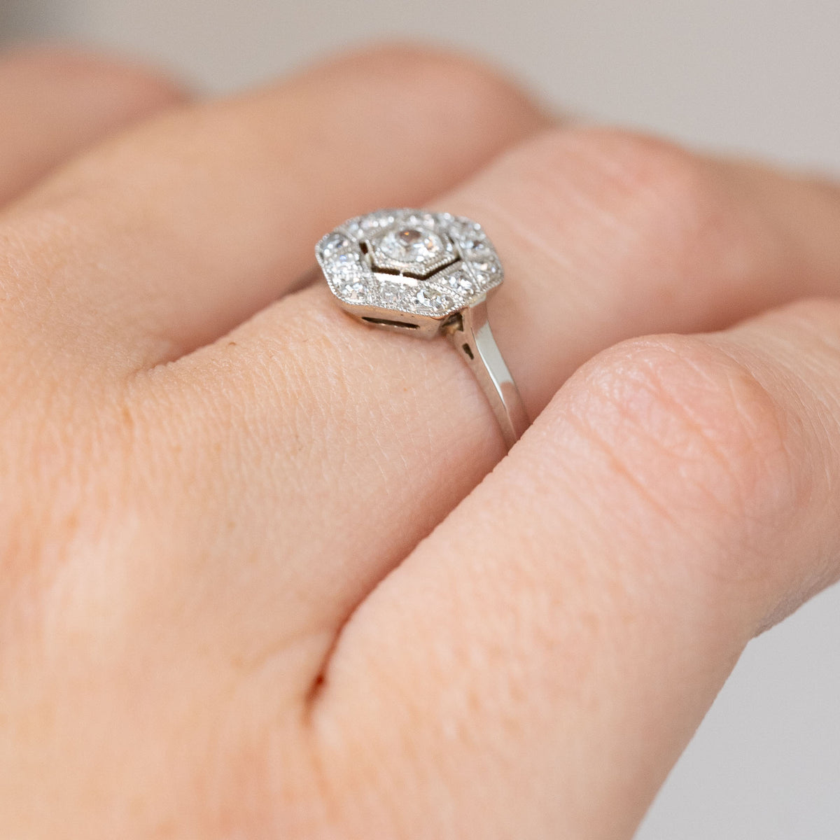 Side angle of the antique engagement ring, revealing its raised cluster setting and delicately tapered shoulders.