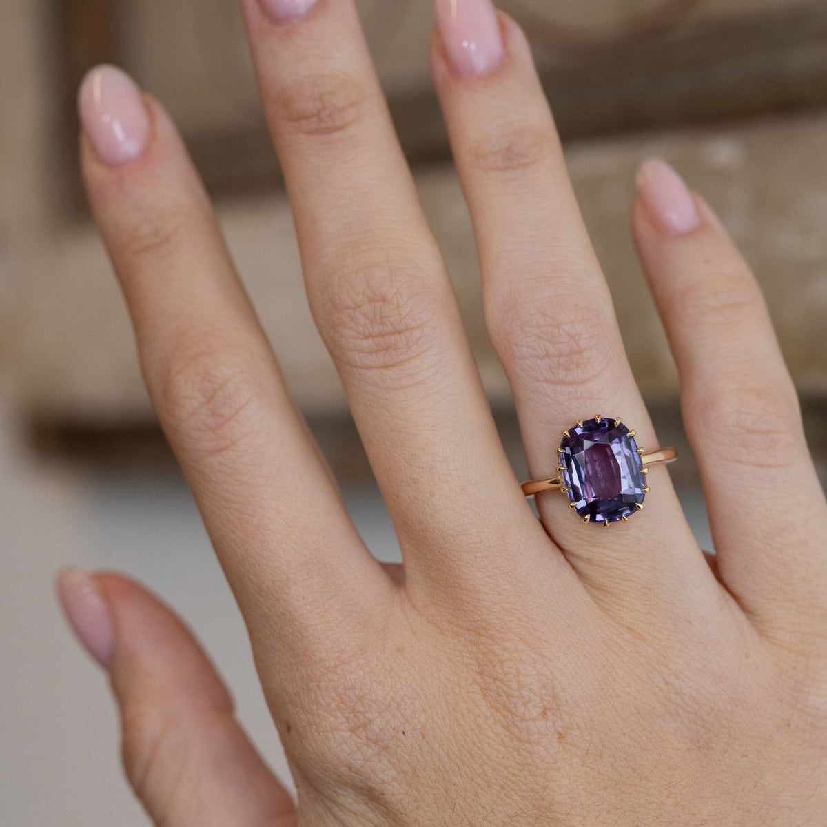 Antique purple sapphire solitaire ring worn on a hand, showcasing its striking gemstone and elegant proportions.