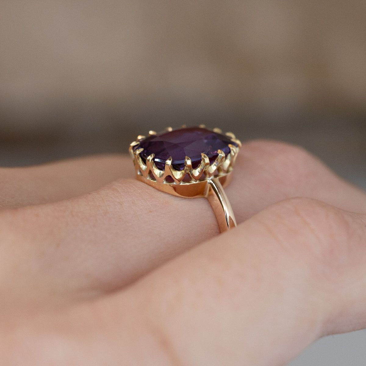 Side-angle view of the sapphire solitaire ring worn on a hand, highlighting the elevated setting and delicate yellow gold band.