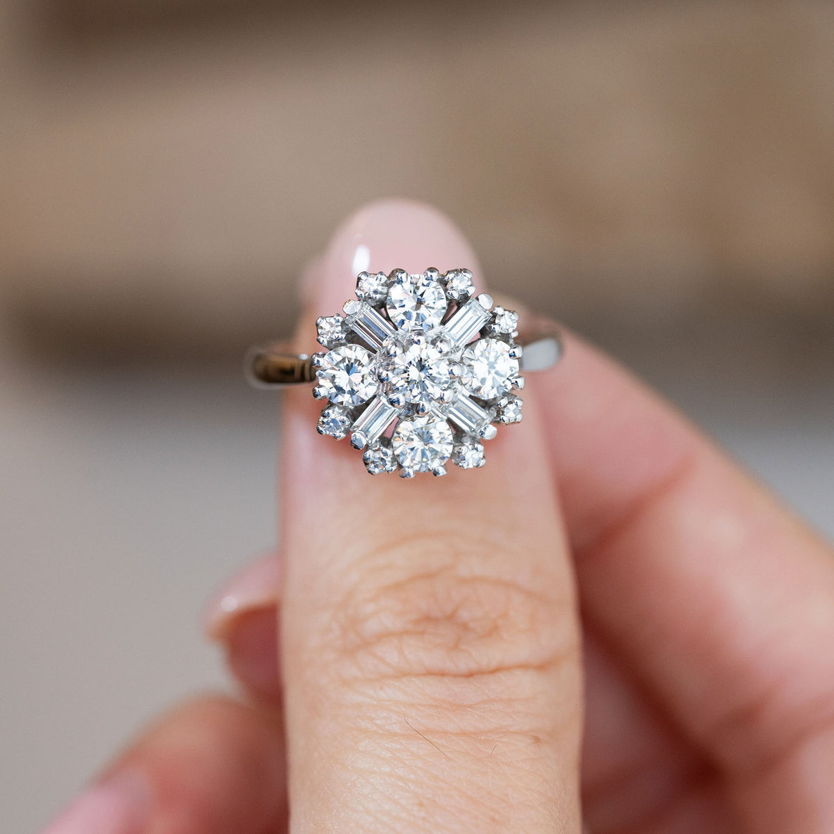 Hand-held close-up of the vintage diamond ring, highlighting the symmetrical arrangement of sparkling diamonds in white gold.