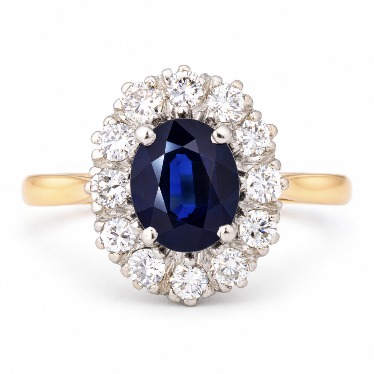 Vintage 1940s dark blue oval sapphire and diamond cluster engagement ring in platinum and yellow gold, surrounded by brilliant-cut white diamonds.