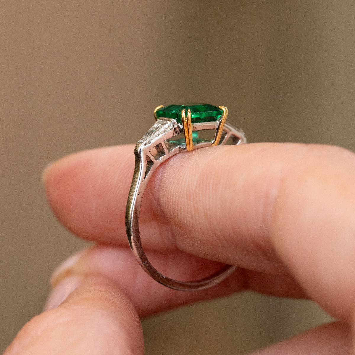 Profile detail of the vintage three-stone ring, revealing the open gallery, yellow gold claws and slender white gold shank.