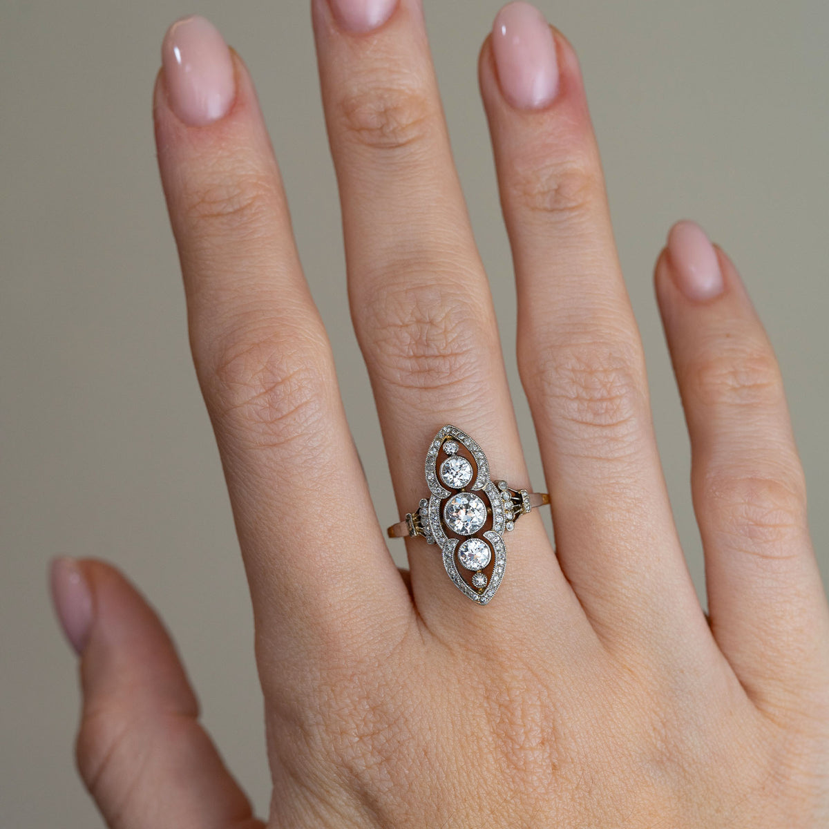 Antique Art Nouveau diamond cluster ring worn on a hand, highlighting its distinctive elongated shape and sparkling vintage diamonds.