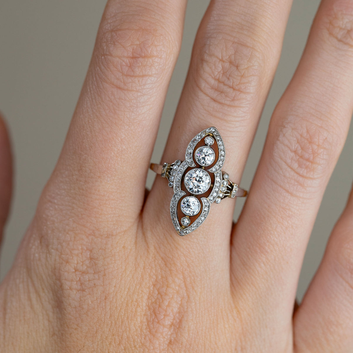 Close-up of the Art Nouveau ring on a finger, showcasing the graduated diamonds framed by a delicate platinum border.