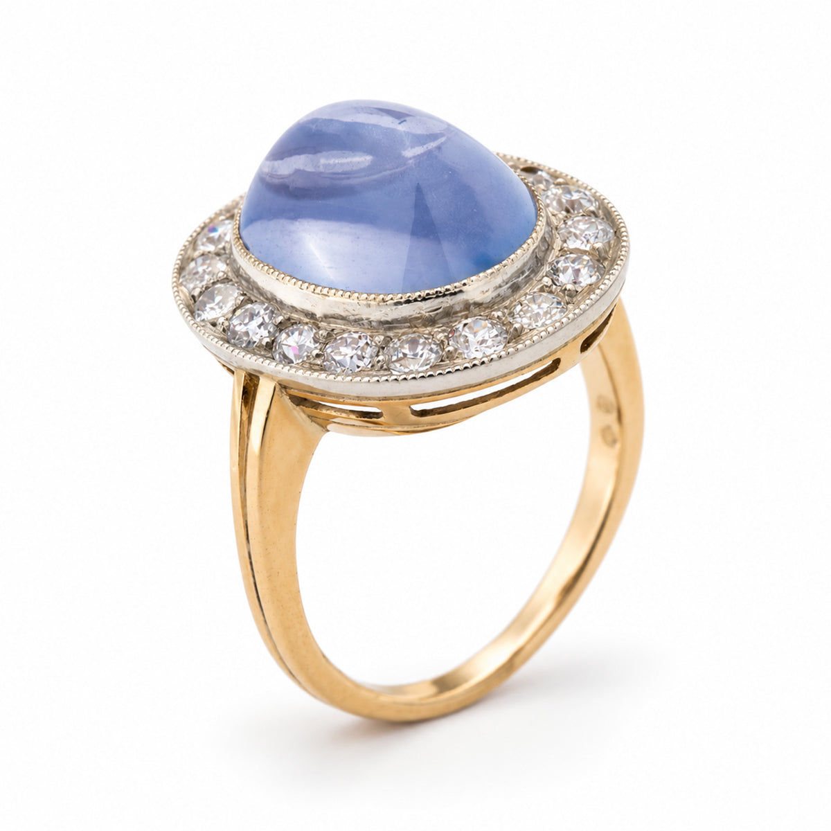 Elevated studio portrait of the Victorian sapphire ring, revealing its domed cabochon, antique diamond halo and yellow gold band.