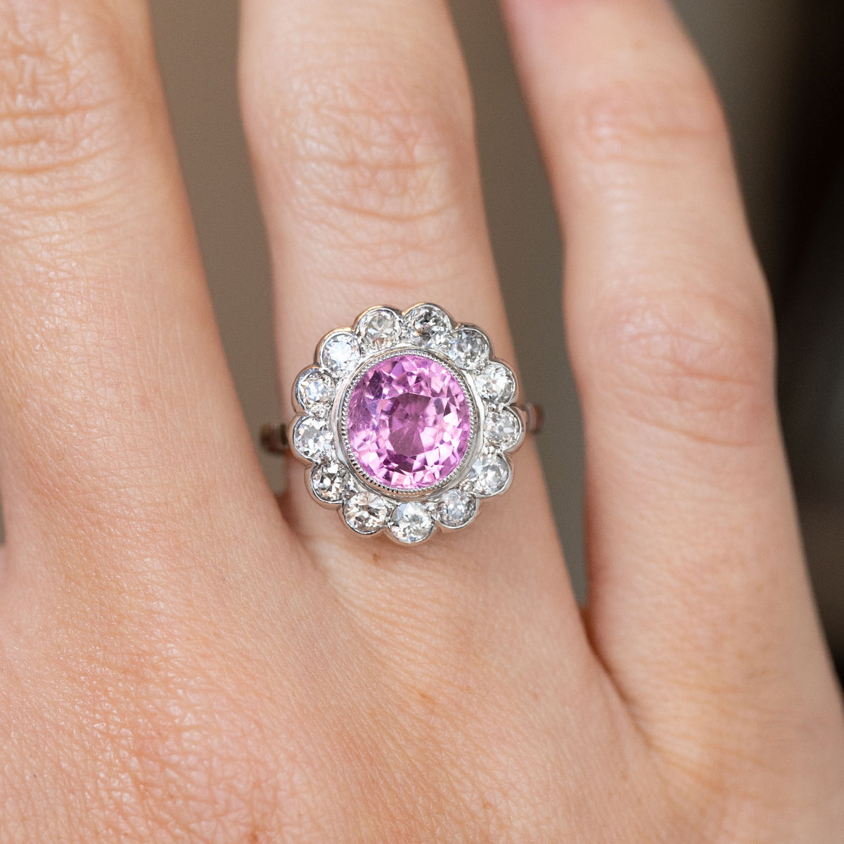 Close-up of the white gold and platinum ring, featuring a cushion-cut pink sapphire encircled by diamonds.