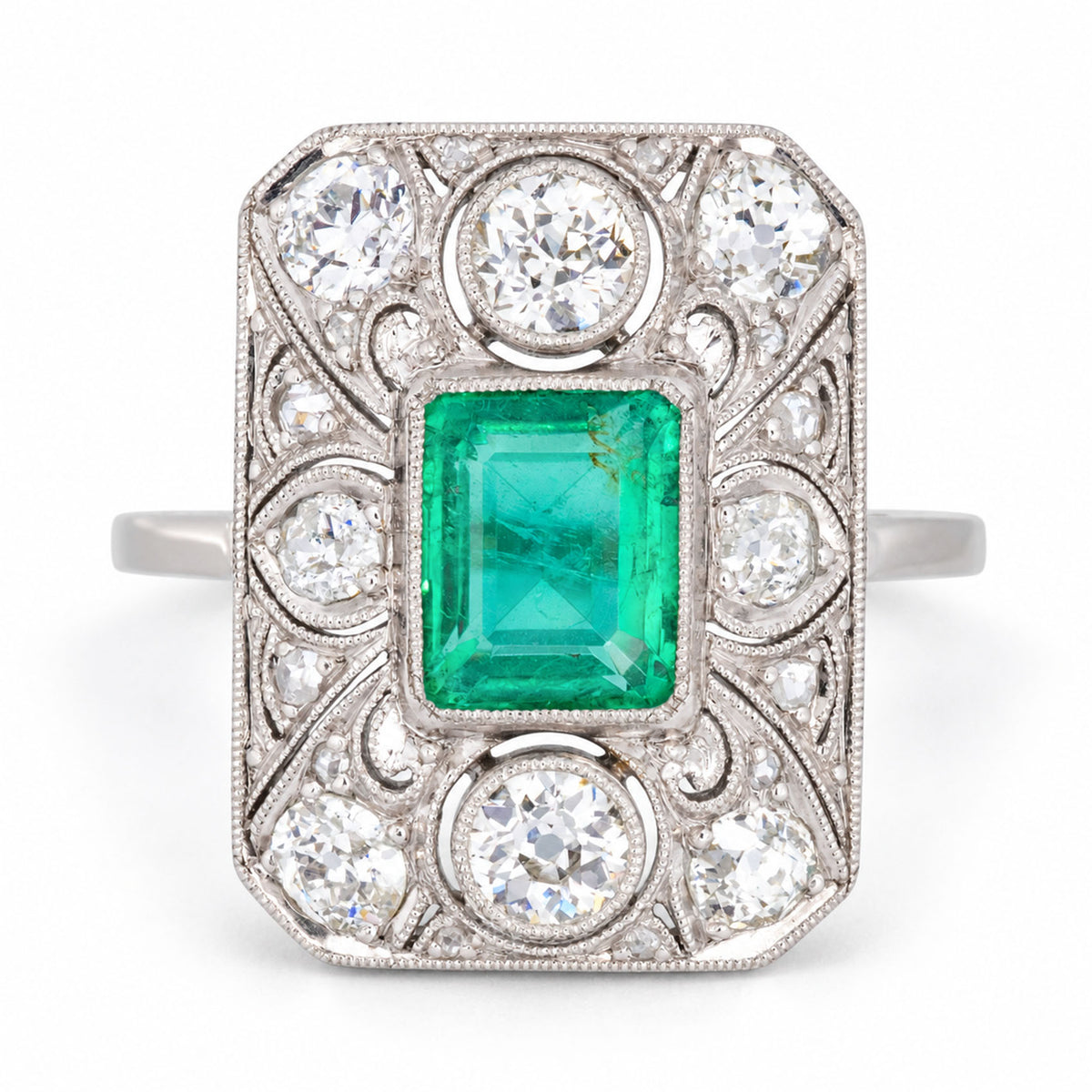 Antique Art Deco Colombian emerald and diamond panel cluster ring in platinum, featuring a rub-over set emerald, old-cut diamonds and intricate filigree lacework.