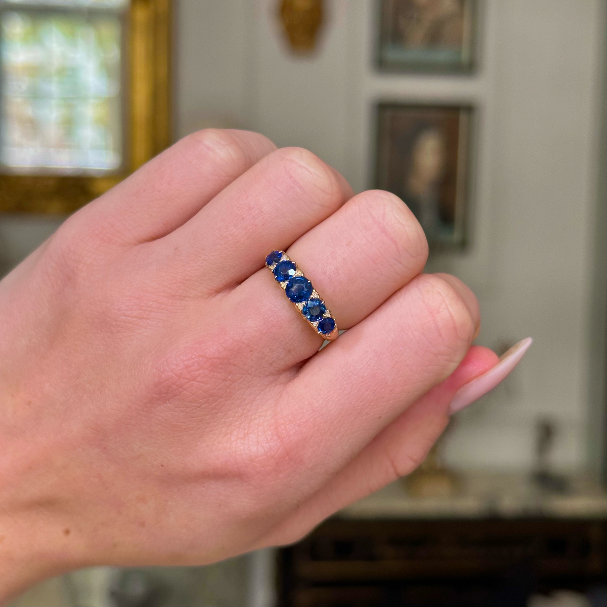 sapphire and diamond five stone ring on closed hand.