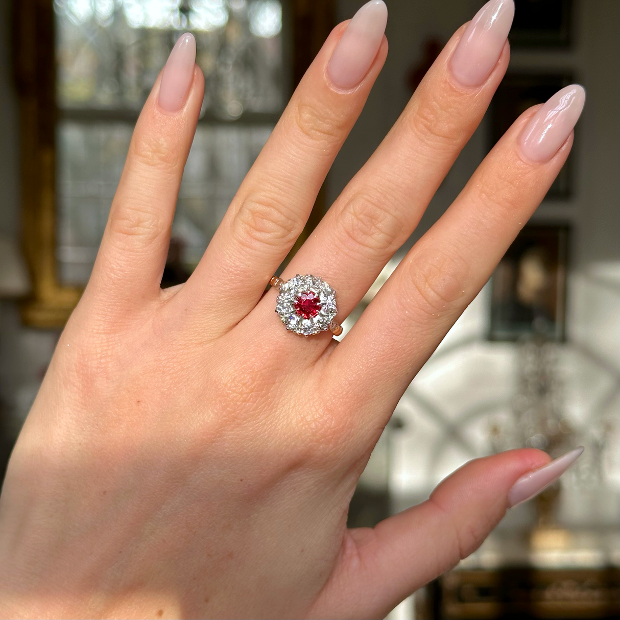 Antique victorian ruby and diamond cluster engagement ring worn on hand.