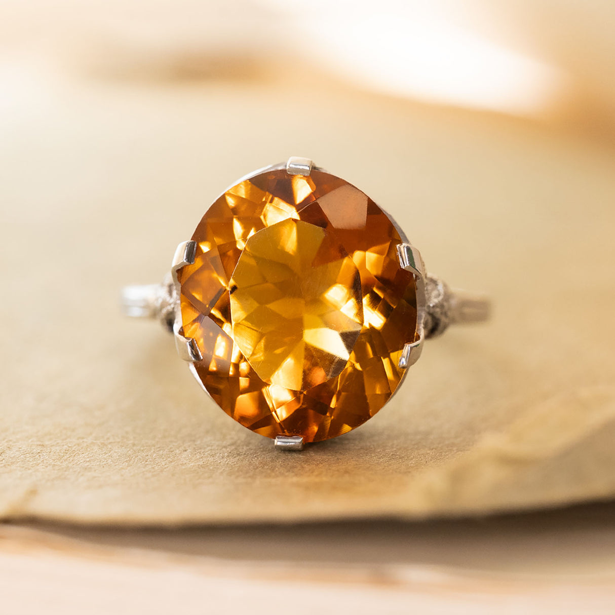 An Antique Art Deco citrine cocktail ring set in platinum displayed on an old book cover.