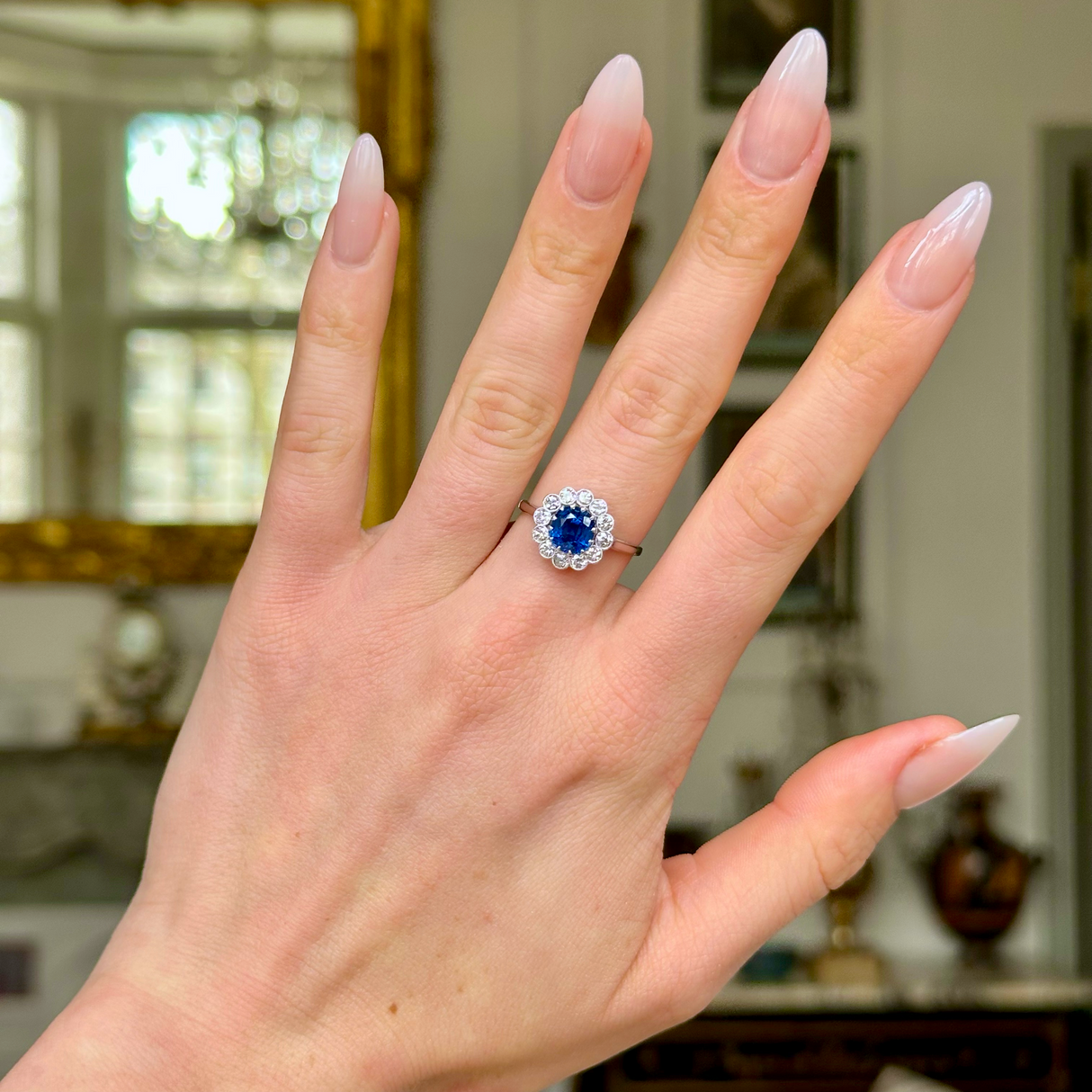 Antique sapphire and diamond cluster ring, worn on hand.