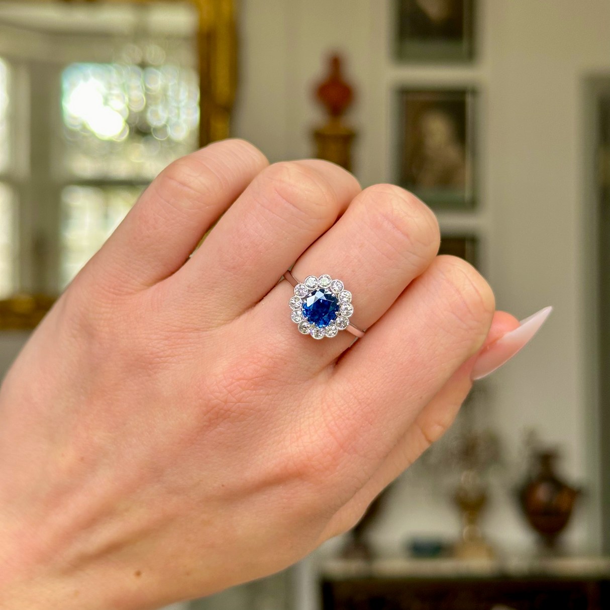 Antique sapphire and diamond cluster ring, worn on closed hand.
