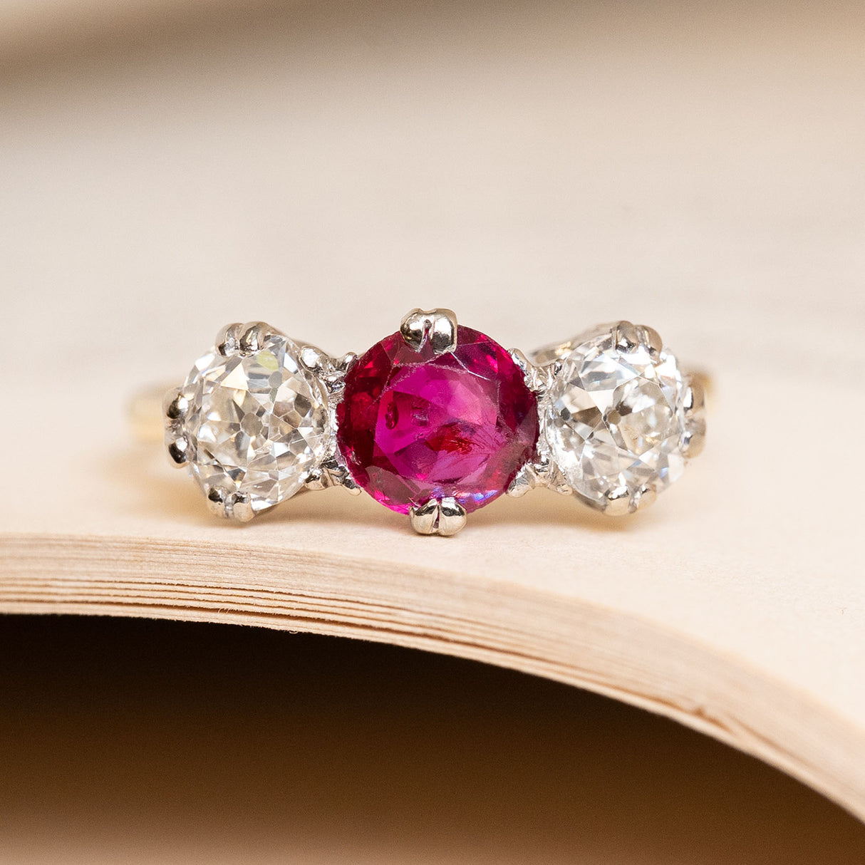 Antique Edwardian Burmese ruby and diamond three-stone ring, with a central ruby flanked by old-mine cut diamonds.