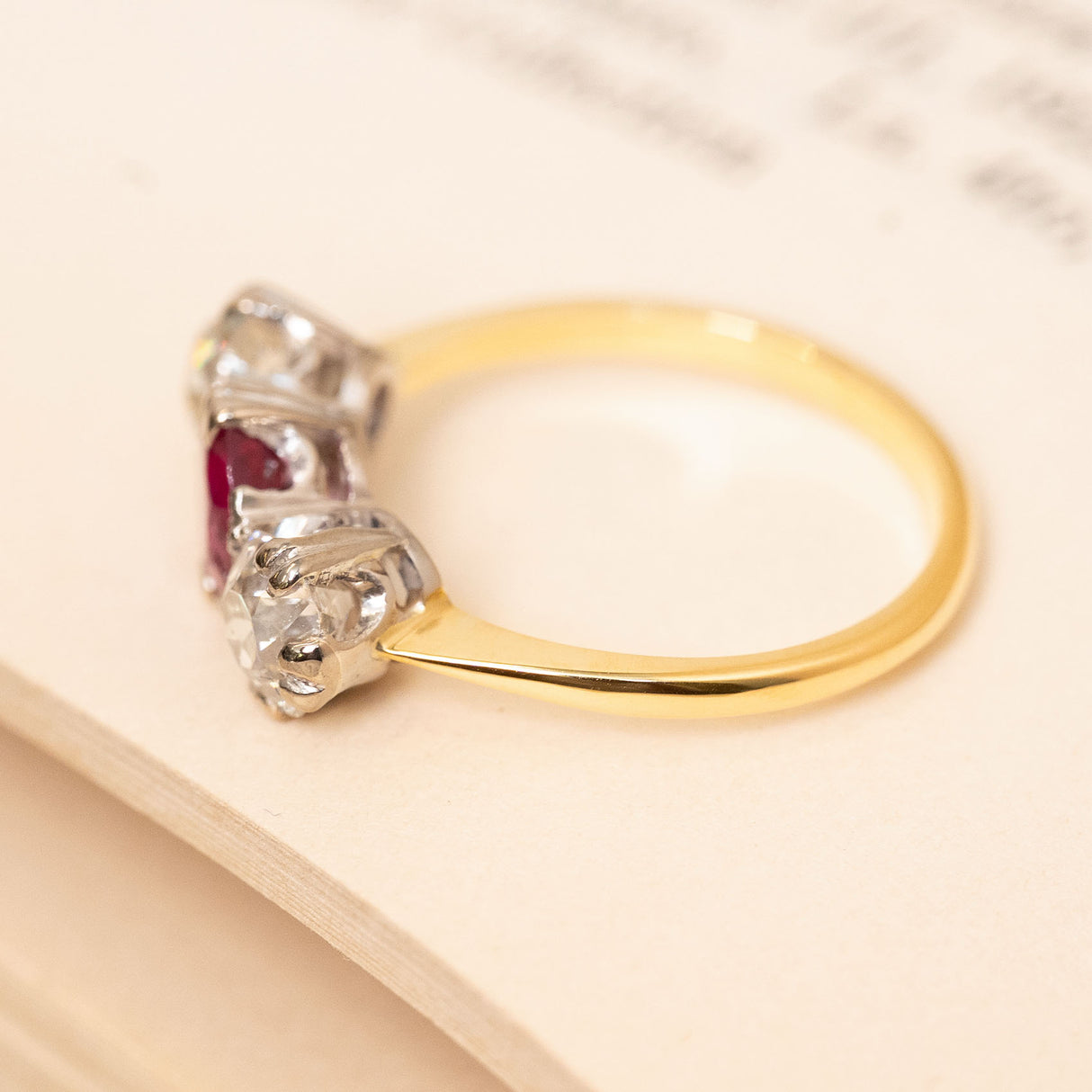 Antique Edwardian Burmese ruby and diamond three-stone ring with a yellow gold band and white gold setting.