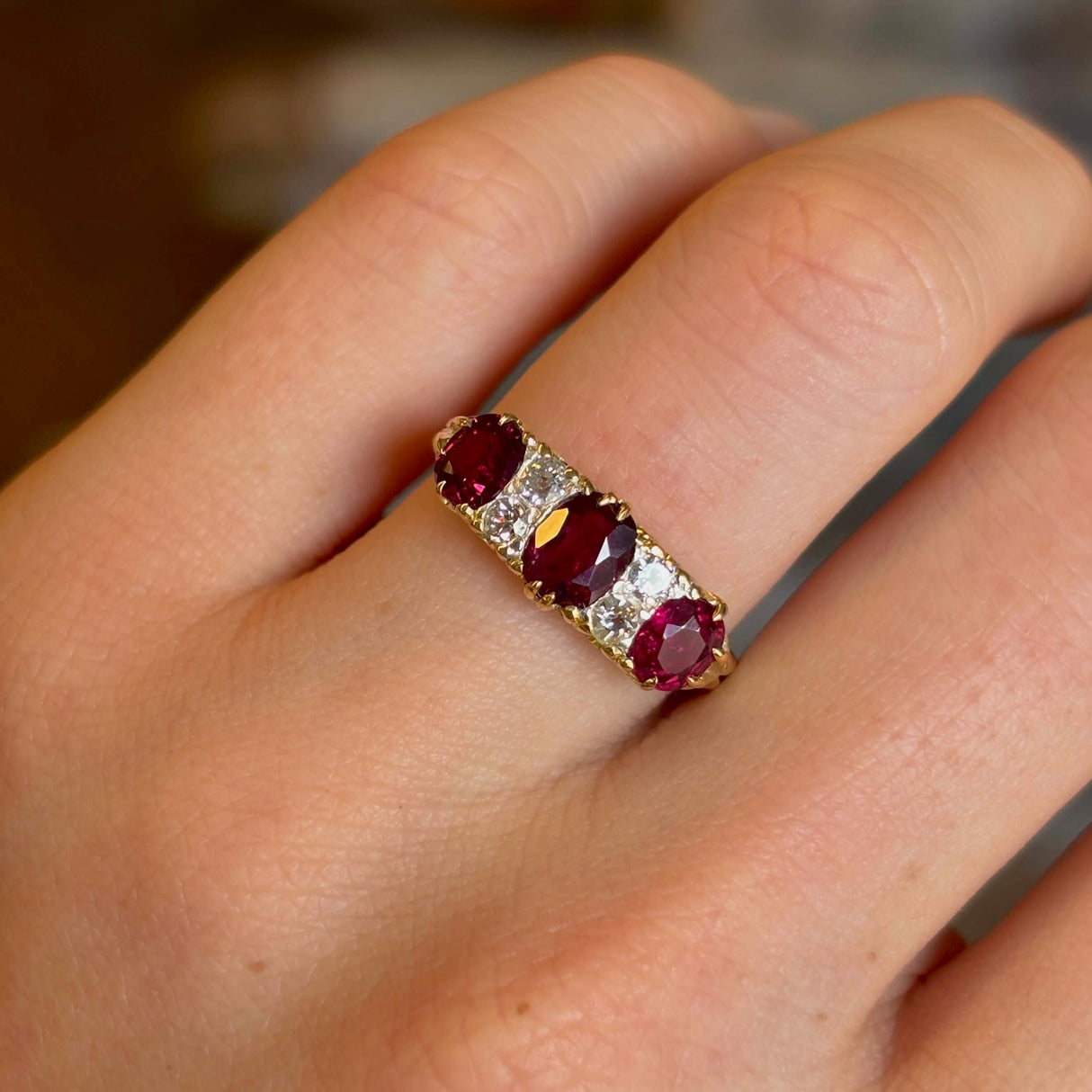 Antique, Victorian ruby and diamond three-stone ring worn on ring finger on left hand close-up